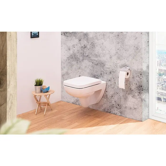 Calmwaters WC-Sitz Renova Nr. 1 Plan - Duroplast, Weiß, Mit Absenkautomatik - Das Bild zeigt eine moderne, wandmontierte Toilette in einem Badezimmer mit Holzboden und einer strukturierten grauen Wand. Ein minimalistisches Design im Fokus.