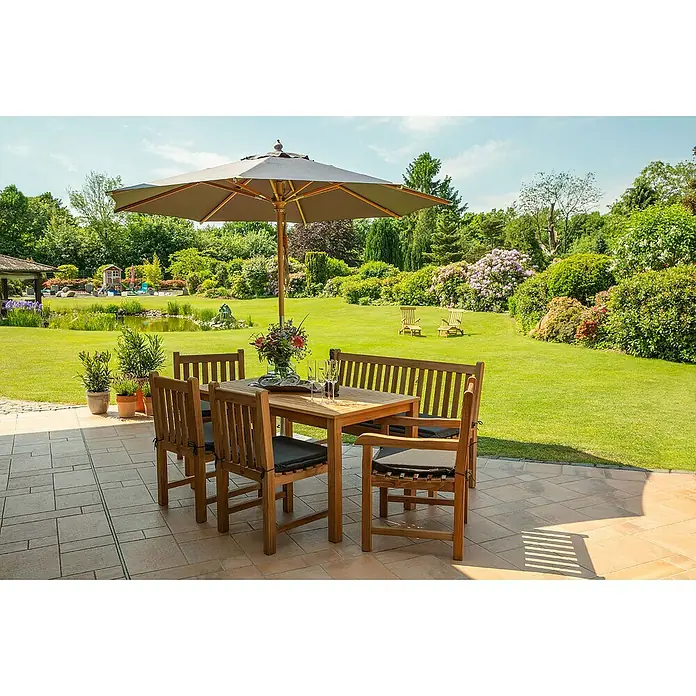 Kai Wiechmann Gartensessel - Teakholz, Naturbelassen, B x T x H: 60 x 63 x 92 cm - Hölzerne Gartentischgruppe mit Sonnenschirm auf einer Steinterrasse, ideal für entspannte Stunden im Grünen. Das Set umfasst Tisch, Stühle und Bank.