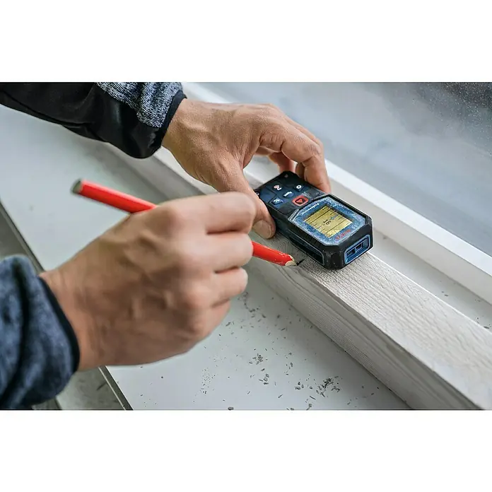Bosch Professional Laserentfernungsmesser GLM 40-31 - Messgenauigkeit: Typisch: ± 1,5 mm, Mit Batterien - Nahaufnahme eines Mannes, der mit einem roten Stift und einem Bosch-Laserentfernungsmesser eine Holzleiste markiert.