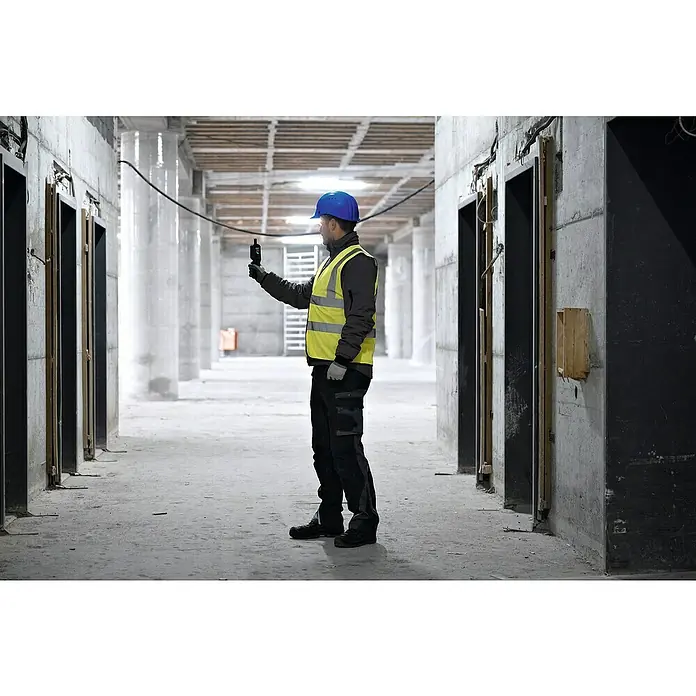 Bosch Thermo-Hygrometer GDH 1-17 - Mit Batterien - Ein Bauarbeiter mit Helm und Warnweste inspiziert einen Rohbau mit einem Gerät in der Hand.