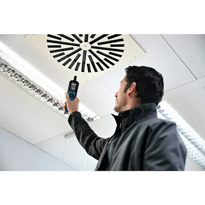 Bosch Thermo-Hygrometer GDH 1-17 - Mit Batterien - Mann misst die Temperatur mit einem Bosch-Thermo-Detektor an der Decke. Das Gerät ist blau und schwarz mit Display.
