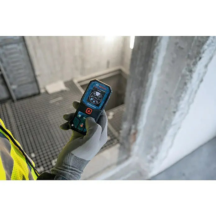 Bosch Professional Laserentfernungsmesser GLM 40-31 - Messgenauigkeit: Typisch: ± 1,5 mm, Mit Batterien - Ein Bosch Professional Entfernungsmesser wird in einer Baustelle gehalten, ein unverzichtbares Werkzeug für präzise Messungen.