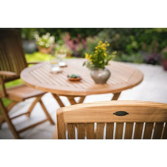 Kai Wiechmann Gartenstuhl - Teakholz, Klappbar, Naturbelassen, B x T x H: 44 x 62 x 96 cm - Nahaufnahme von Gartenmöbeln aus Teakholz, bestehend aus einem runden Tisch und passenden Stühlen, ideal für entspannte Stunden im Freien.