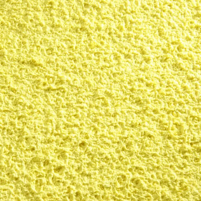 Floxxan Baumwollputz Colorado 114 - Putz Tapete Flüssigtapete Mais - Mais, 1 kg, Lösemittelfrei - Nahaufnahme eines gelben Reinigungsschwamms mit unregelmäßiger, poröser Textur, ideal zum Schrubben und Reinigen von Oberflächen.