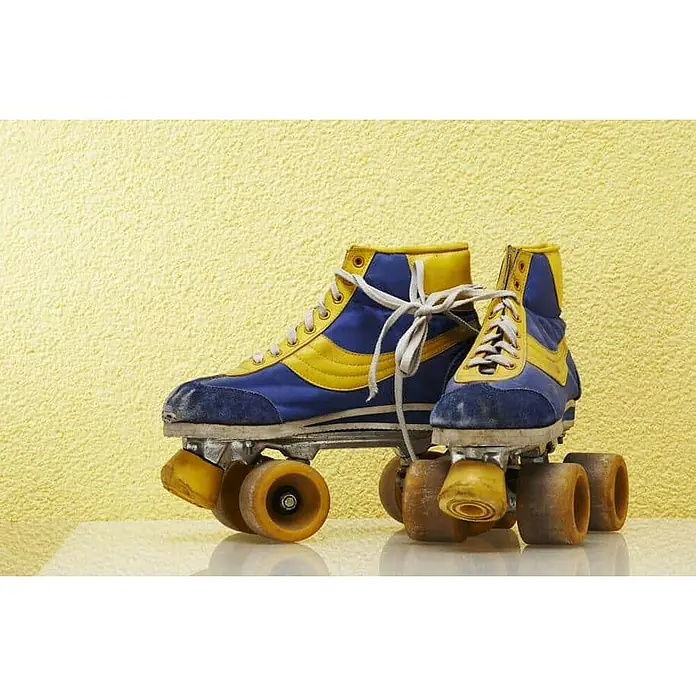 Floxxan Baumwollputz Colorado 114 - Putz Tapete Flüssigtapete Mais - Mais, 1 kg, Lösemittelfrei - Nahaufnahme von Retro-Rollschuhen in Blau und Gelb mit abgenutzten Rädern, die Nostalgie und Spaß wecken.