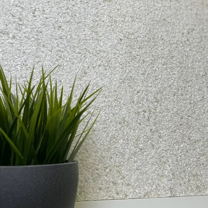 Floxxan Baumwollputz Montana 507 Cellulose - Putz Tapete Flüssigtapete Sand - Sand, 1 kg, Lösemittelfrei - Nahaufnahme einer Kunstpflanze im Topf vor einer strukturierten, hellen Wand. Ideale Dekoration für jeden Raum und ein echter Hingucker.
