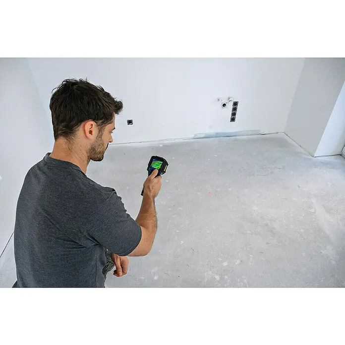 Bosch Professional Wärmebildkamera GTC 12V-450-13 Solo - -20 °C - 450 °C - Ein Mann inspiziert einen Raum mit einer Wärmebildkamera, die Temperaturen auf dem Display anzeigt. Das Werkzeug hilft bei der Bauinspektion.