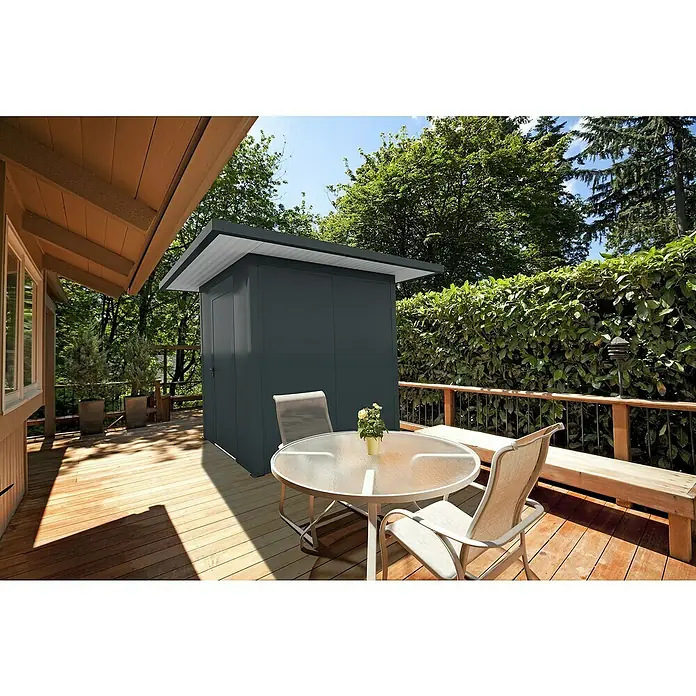Wismar-NFI Gerätehaus Aster 1V - Außenmaß inkl. Dachüberstand (B x T): 225 x 225 cm, Stahl, Anthrazit/Weiß, Einzeltür - Außenaufnahme eines stilvollen, grauen Gartenhauses mit Flachdach, das auf einer Holzterrasse neben einem Tisch und Stühlen steht.