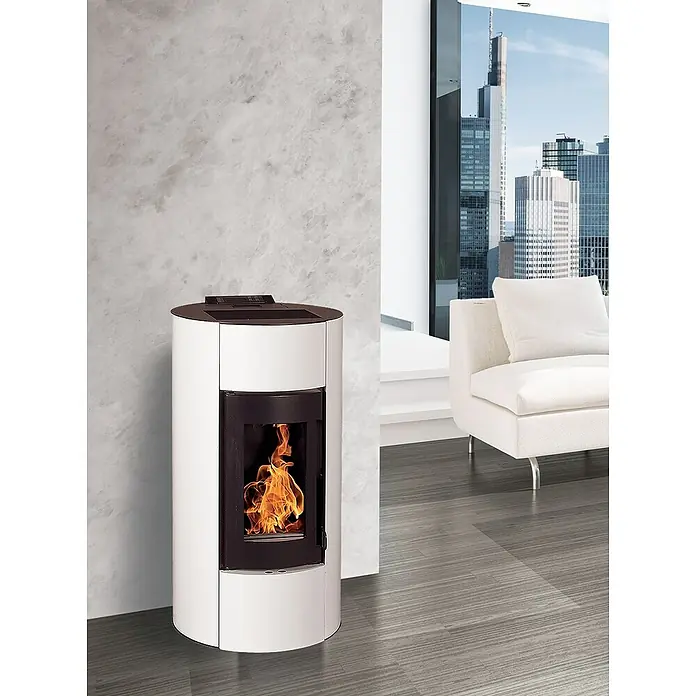 Pelletofen Angelina - 11,4 kW, Raumheizvermögen: 320 m³, 0,73 kg/h - 2,5 kg/h, Farbe Verkleidung: Weiß - Ein moderner, weißer Pelletofen mit sichtbaren Flammen in einem stilvollen Wohnzimmer mit großem Fenster und Stadtaussicht.