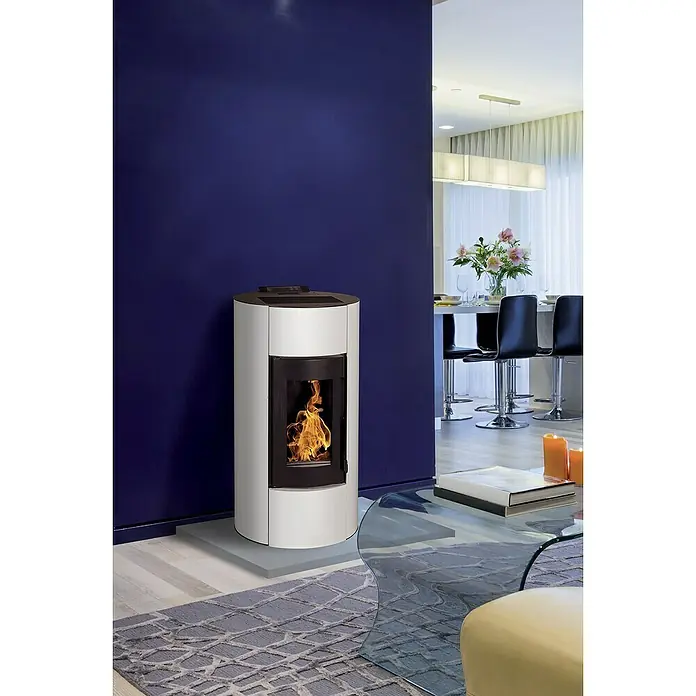 Pelletofen Angelina - 8,9 kW, Raumheizvermögen: 250 m³, 0,73 kg/h - 1,96 kg/h, Farbe Verkleidung: Weiß - Kaminofen in modernem Design. Der Ofen ist weiß mit schwarzem Rahmen und steht vor einer blauen Wand in einem eleganten Wohnzimmer.