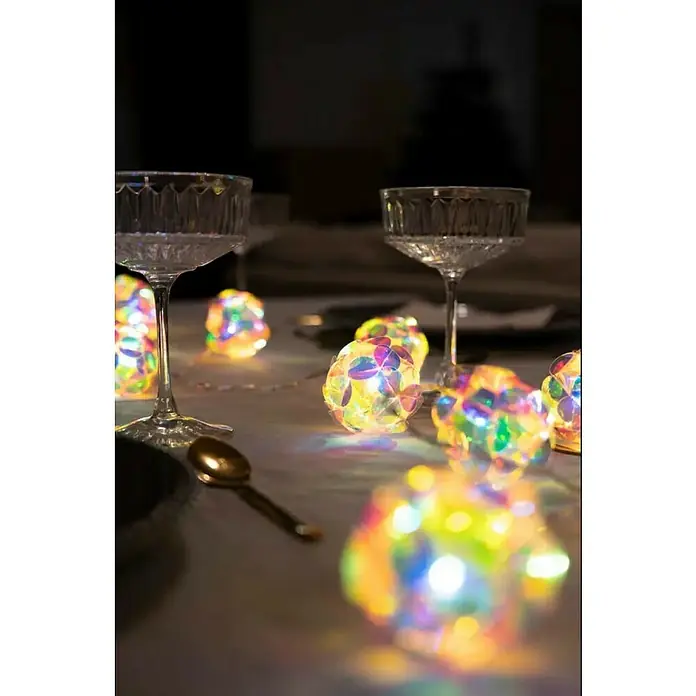 Konstsmide LED-Lichterkette - Innen, Lichtfarbe: Warmweiß, Anzahl Leuchtmittel: 10 Stk., Batteriebetrieben, LED - Dekorative Tischszene mit eleganten Champagnergläsern und schimmernden Lichtkugeln, die eine festliche und warme Atmosphäre schaffen.
