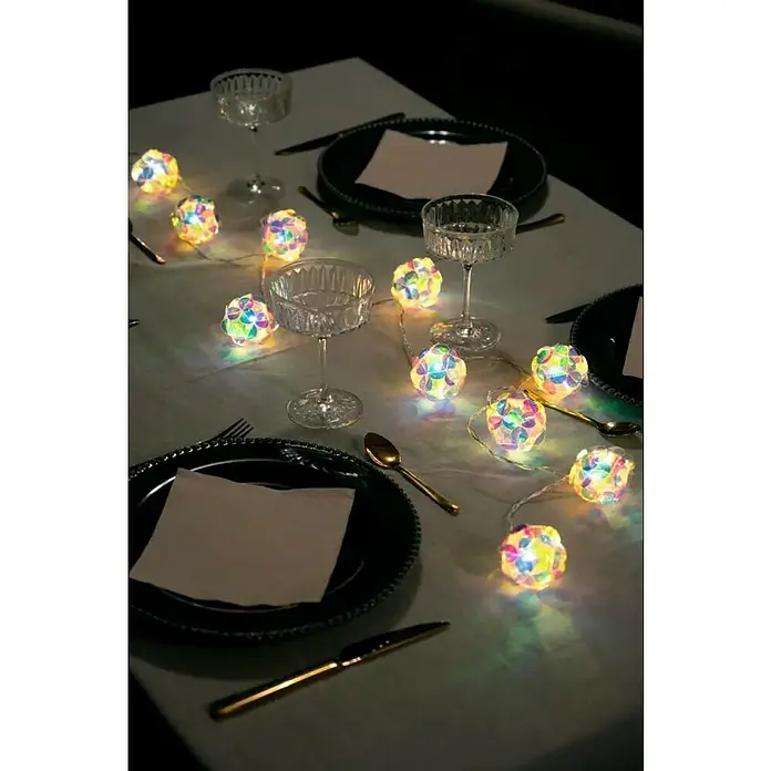 Konstsmide LED-Lichterkette - Innen, Lichtfarbe: Warmweiß, Anzahl Leuchtmittel: 10 Stk., Batteriebetrieben, LED - Festlich gedeckter Tisch mit bunten Lichterketten, eleganten Tellern und goldenem Besteck für eine besondere Atmosphäre.
