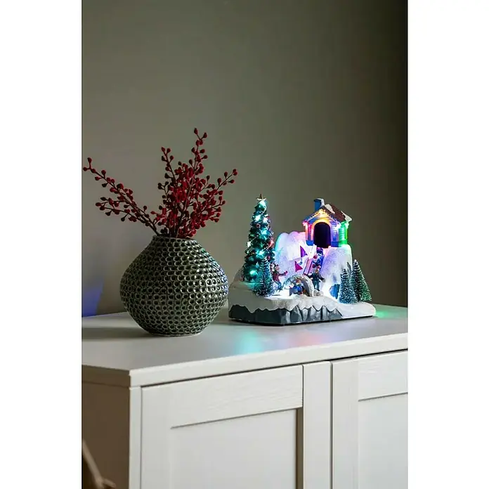 Konstsmide LED-Szenerie Rodelbahn - 21,5 x 13 x 18,5 cm, Mehrfarbig, Batteriebetrieben, LED - Dekoratives Arrangement mit einer Blumenvase und einem beleuchteten Weihnachtsminiaturdiorama, das eine festliche Atmosphäre schafft.