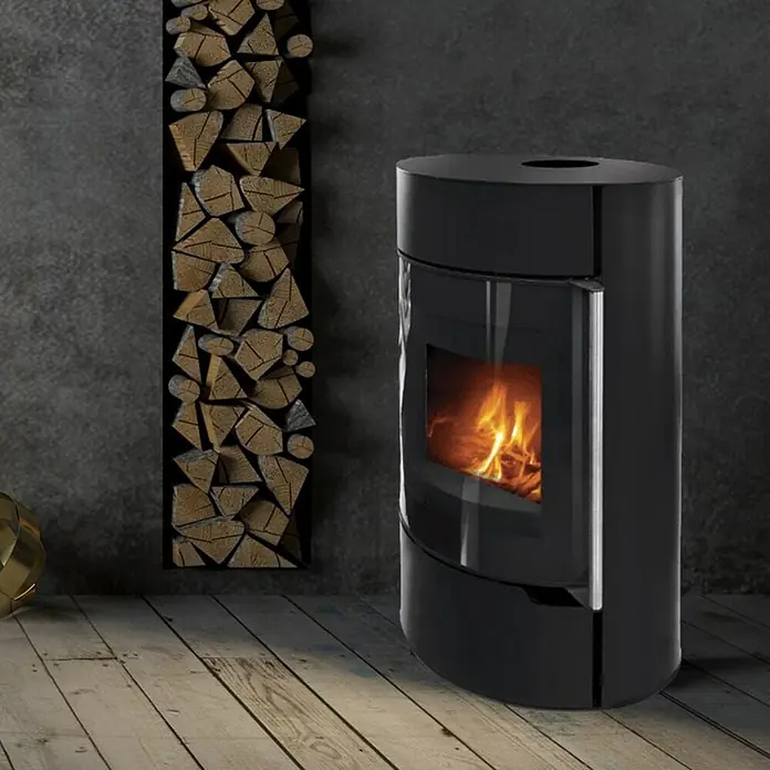 Kaminofen Nella - 10,3 kW, Raumheizvermögen: 295 m³, Schwarz - Schwarzer Kaminofen mit Glasfenster und Holzscheitwand für ein gemütliches Ambiente.