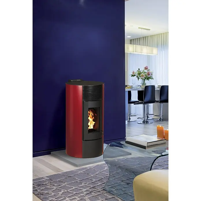 Pelletofen Paola 9 - 8,9 kW, Raumheizvermögen: 250 m³, 0,73 kg/h - 1,96 kg/h, Farbe Verkleidung: Bordeaux - Ein moderner Pelletofen in Rot und Schwarz steht auf einem grauen Sockel in einem stilvollen Wohnzimmer und sorgt für Wärme und Atmosphäre.