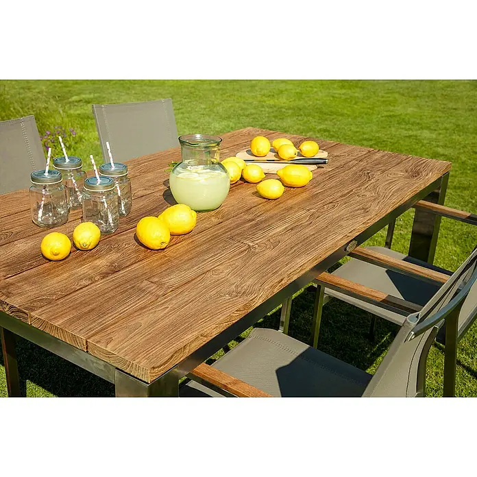 Kai Wiechmann Gartentisch - L x B x H: 220 x 100 x 76,5 cm, Teak, Rechteckig, Naturbelassen - Ein Gartentisch mit Stühlen, Gläsern, Zitronen und einer Karaffe Limonade im Freien. Die Tischplatte ist aus Holz und das Gestell aus Metall.