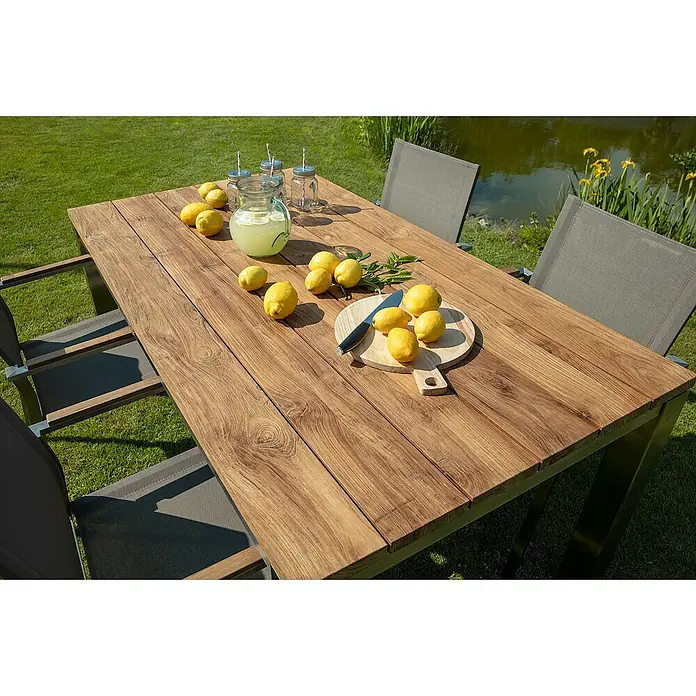 Kai Wiechmann Gartentisch - L x B x H: 220 x 100 x 76,5 cm, Teak, Rechteckig, Naturbelassen - Nahaufnahme eines Teakholztisches mit Stühlen, Zitronen, Getränken und einem Teich im Hintergrund.