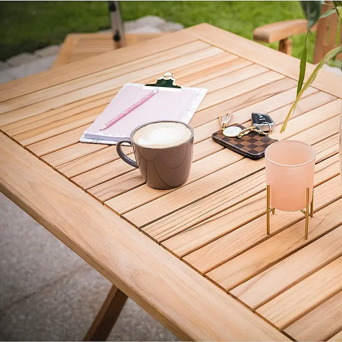 Kai Wiechmann Gartentisch - L x B x H: 120 x 70 x 75 cm, Teakholz, Rechteckig, Naturbelassen - Nahaufnahme eines quadratischen Holztisches mit einer Tasse Kaffee, Notizblock, Schlüsseln und einer Kerze.