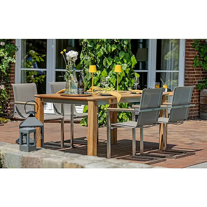 Kai Wiechmann Gartentisch - L x B x H: 165 x 90 x 77 cm, Teak, Rechteckig, Naturbelassen - Ein einladender Gartentisch mit Stühlen, dekoriert mit Blumen, Getränken und gelben Akzenten, perfekt für Mahlzeiten im Freien.
