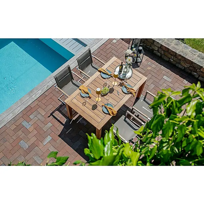 Kai Wiechmann Gartentisch - L x B x H: 165 x 90 x 77 cm, Teak, Rechteckig, Naturbelassen - Ein quadratischer Esstisch aus Holz mit vier Stühlen auf einer Terrasse neben einem Pool, gedeckt mit Geschirr, Gläsern und Dekorationen.
