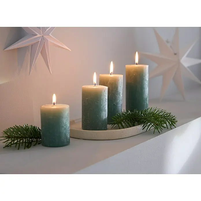 Stumpenkerzen-Set Rustic Safe - 4 -tlg., Smaragd - Adventsstimmung: Vier grüne Kerzen auf einem Teller mit Tannenzweigen, umgeben von weißen Papiersternen für eine festliche Dekoration.