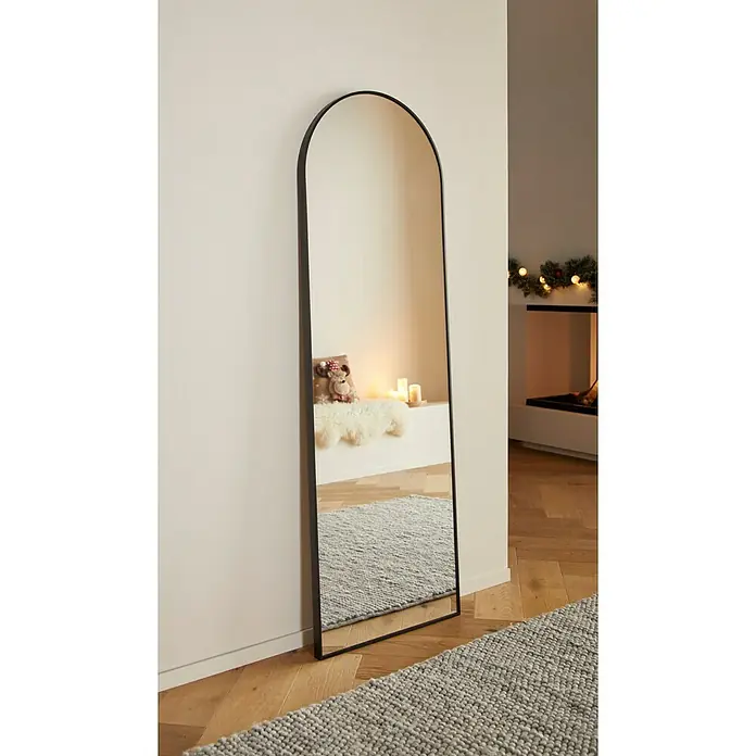 Rahmenspiegel Malva - 50 x 150 cm, Schwarz, Aluminium - Elegante Ganzkörperspiegel mit abgerundetem Rahmen. Der Spiegel lehnt an der Wand und reflektiert ein gemütliches Interieur.