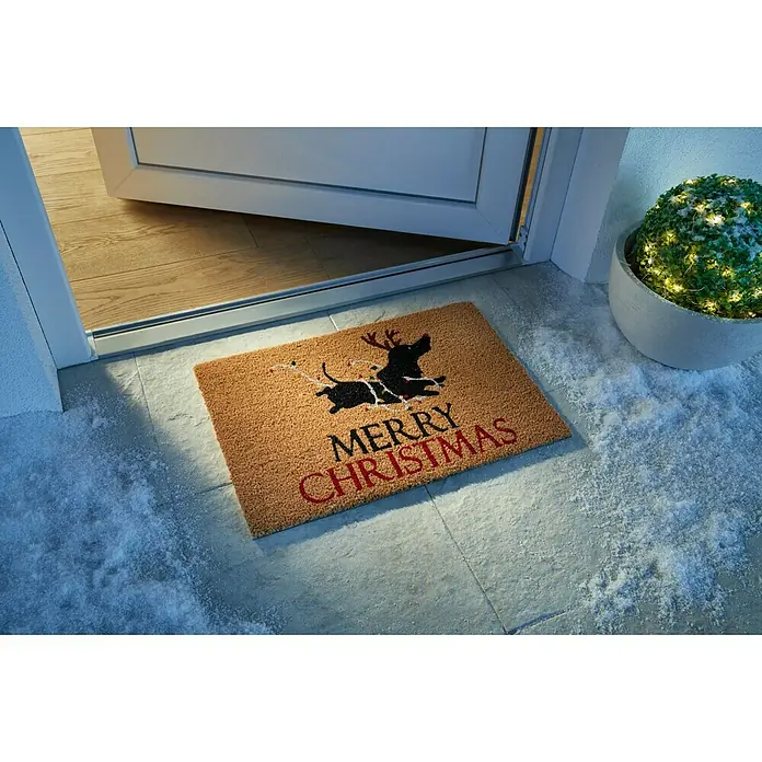Fußmatte - 60 x 40 cm, Braun/Schwarz, Material Nutzschicht: 100 % Kokos, Dackel X-Mas, Kokos - Eine festliche Fußmatte mit einem Dackel mit Geweih und "Merry Christmas" Schriftzug liegt vor einer teilweise geöffneten Tür.