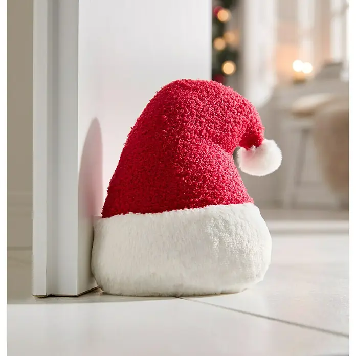 Türstopper Santa Xmas - 18 x 12 x 21 cm, Rot/Weiß - Ein festlicher Türstopper in Form einer Nikolausmütze, rot und weiß, lehnt an einer Tür.