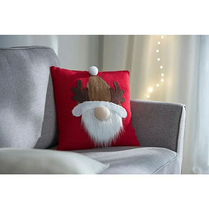 Kissen Santa - Rot, L x H: 40 x 40 cm - Ein rotes Kissen mit einem lustigen Weihnachtswichtel-Design auf einem grauen Sofa.