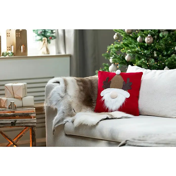 Kissen Santa - Rot, L x H: 40 x 40 cm - Nahaufnahme eines Sofas mit einem roten Kissen mit weihnachtlichem Wichteldesign und einem Fellüberwurf, weihnachtliche Dekoration im Hintergrund.