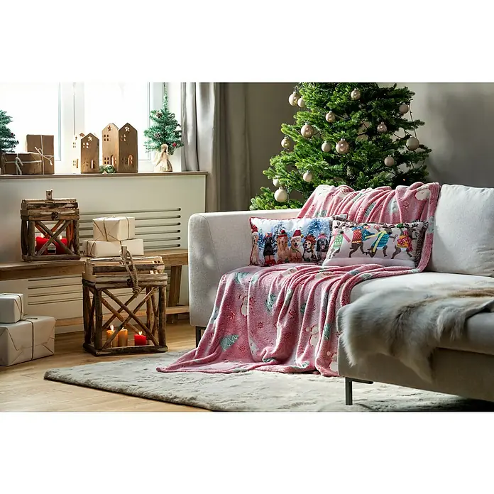 Kissen Rentiere - Weihnachten, 50 x 30 cm, 100 % Polyester - Gemütliche Weihnachtsdekoration mit einem rosa Überwurf, Kissen und einem Weihnachtsbaum, die eine festliche Atmosphäre schaffen.