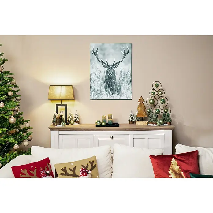 Stumpenkerzen-Set Rustic Safe - 4 -tlg., Smaragd - Ein Wohnzimmer mit einem Hirschbild über einem Sideboard mit Weihnachtsdekoration, was eine festliche und gemütliche Atmosphäre schafft.