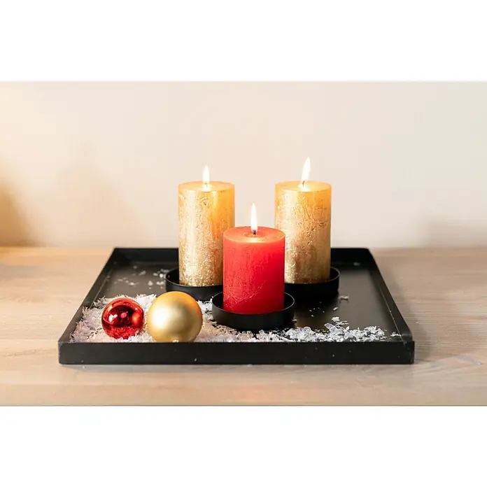 Stumpenkerze Nova Safe - Ø x H: 6 x 11 cm, Antikgold - Dekoratives Tablett mit brennenden Kerzen in Gold und Rot, umgeben von glitzernden Ornamenten, die eine warme, festliche Atmosphäre schaffen.
