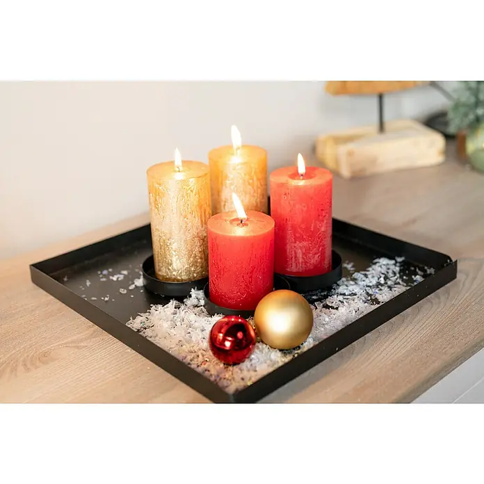 Stumpenkerzen-Set Rustic Safe - 4 -tlg., Rubin - Festliches Arrangement mit goldenen und roten Kerzen auf einem schwarzen Tablett, dekoriert mit glitzerndem Schnee und Weihnachtskugeln.