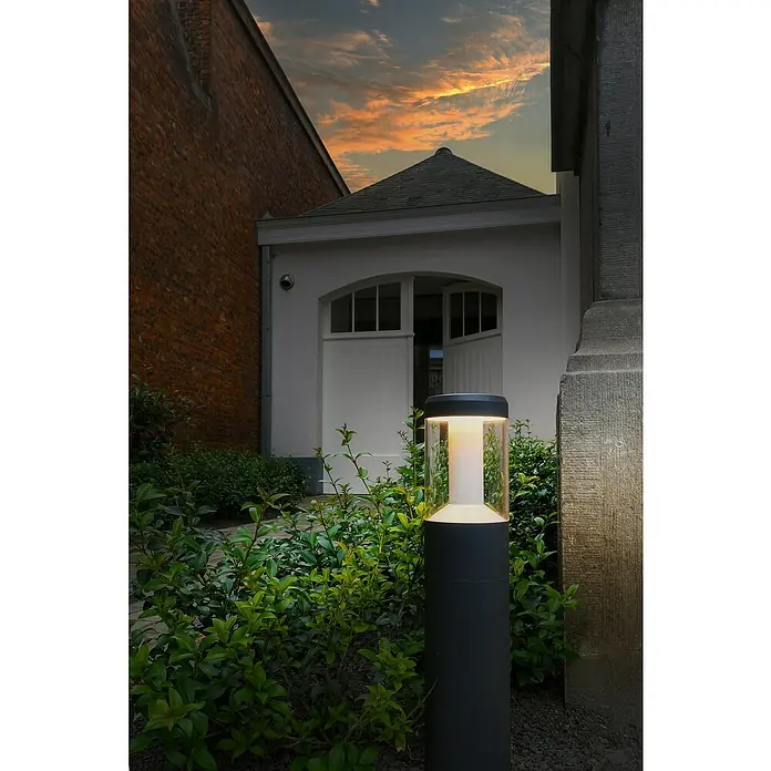 Osram Endura Style Lámpara de pie para exterior Lantern Modern - 12 W, Color del marco: Gris oscuro, Blanco cálido, Con bombillas - Elegante lámpara de exterior negra con luz blanca cálida en medio de un jardín verde, creando un ambiente acogedor.