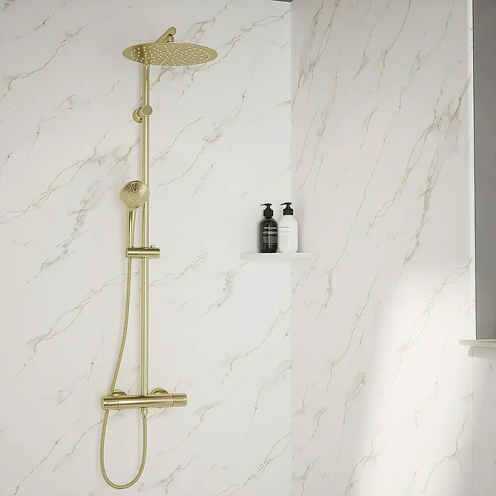 Wetwall Wandpaneel Elite - 16 x 242 cm, Bianco Carrara, Abgerundete Kante - Elegantes Badezimmer-Setup mit einer goldenen Duscharmatur, die Luxus und Stil in Ihr Badezimmer bringt. Zwei stilvolle Flaschen auf einem Regal.