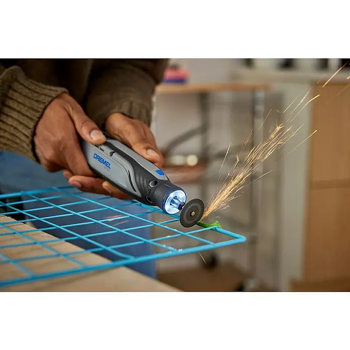 Dremel Akku-Multifunktionswerkzeug 8150-20 - 7,2 V, 1 Akku, 2 Ah - Nahaufnahme eines Dremel Multifunktionswerkzeugs in Aktion, das Funken sprüht, während es an einem blauen Metallgitter arbeitet.