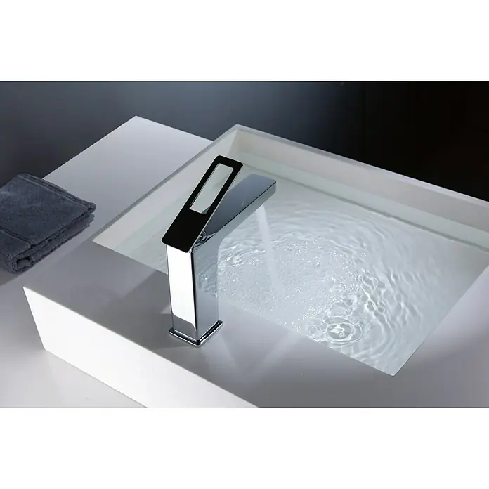 Imex Suecia Grifo de lavabo - Cromo, Brillante - Moderno grifo cromado sobre un lavabo rectangular con agua que fluye, una toalla gris se ve al lado.