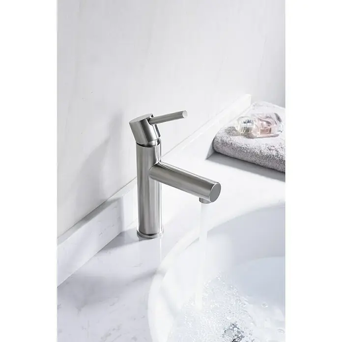 Imex Moscú Grifo de lavabo - Cromo, Resplandeciente - Primer plano de un moderno grifo de baño de níquel cepillado con grifo que fluye sobre una encimera de mármol que muestra un elegante diseño de baño.