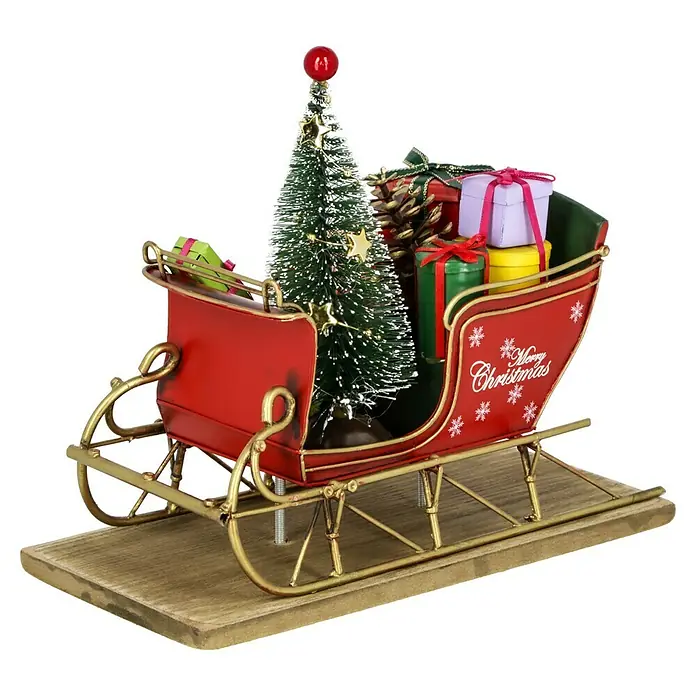 Dekofigur Weihnachtsschlitten - L x B x H: 22 x 10,5 x 18 cm, Metall - Weihnachtsdekoration mit einem roten Schlitten, gefüllt mit Geschenken, einem Weihnachtsbaum und Tannenzapfen, auf einem Holzsockel.