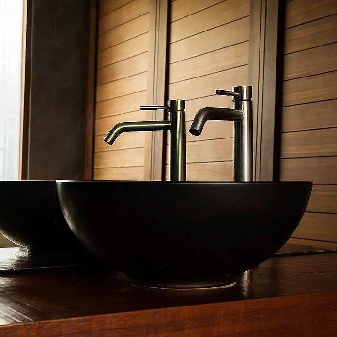 LuxeBath Aufsatzwaschbecken Aufsatzwaschtisch Spülbecken inkl. Ablaufgarnitur ohne Überlauf Becken - Ohne Spezialglasur, Schwarz - Elegante schwarze Waschbecken mit modernen Armaturen vor einer Holzwand. Stilvolles Badezimmerdesign für ein luxuriöses Ambiente.