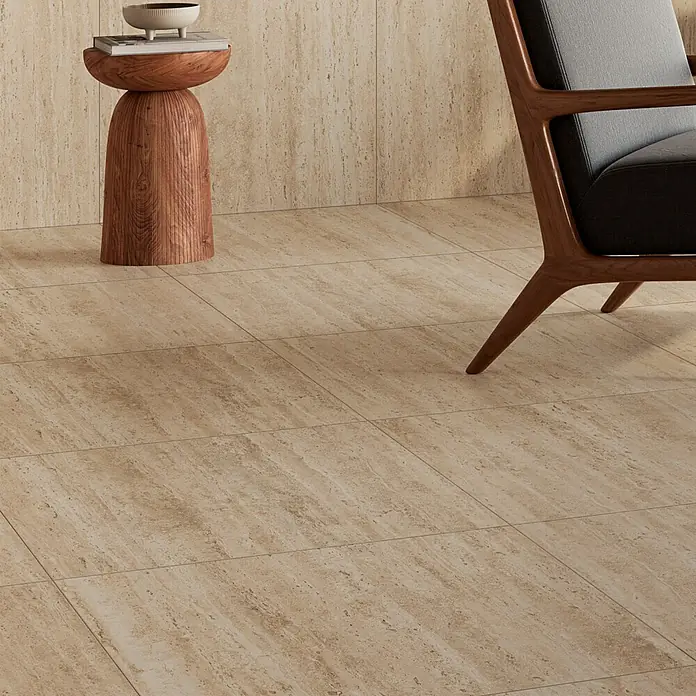 Atlas Concorde Solution Feinsteinzeugfliese Pompei Aureo Classic - 60 x 60 cm, Hellbraun, Matt - Nahaufnahme eines modernen Raumes mit beigen Bodenfliesen, einem eleganten Sessel und einem dekorativen Beistelltisch aus Holz.