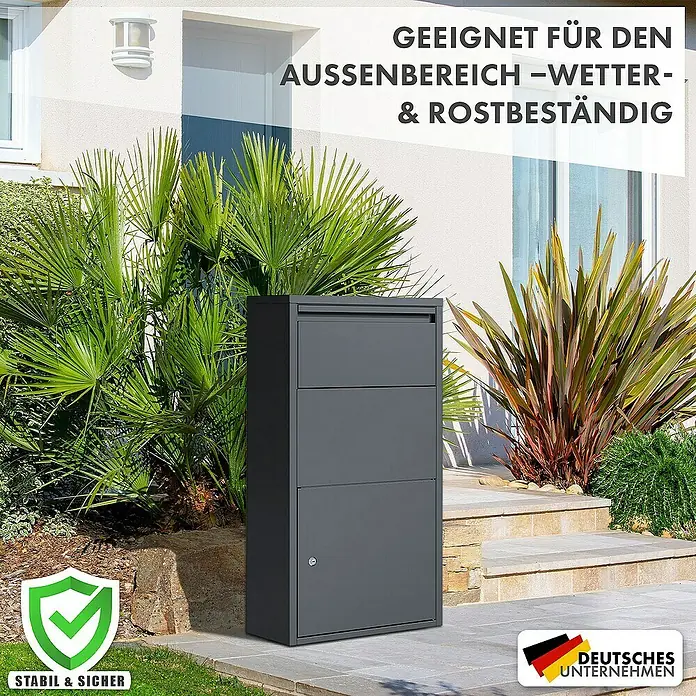 Floordirekt Paketbox Clement mit Klappsystem und Schloss - L x B x H: 22 x 44 x 82 cm, Anthrazit, Stahl, Paketfach - Ein grauer Standbriefkasten aus Metall, wetter- und rostbeständig, ideal für den Außenbereich, vor einem Haus mit grünen Pflanzen.