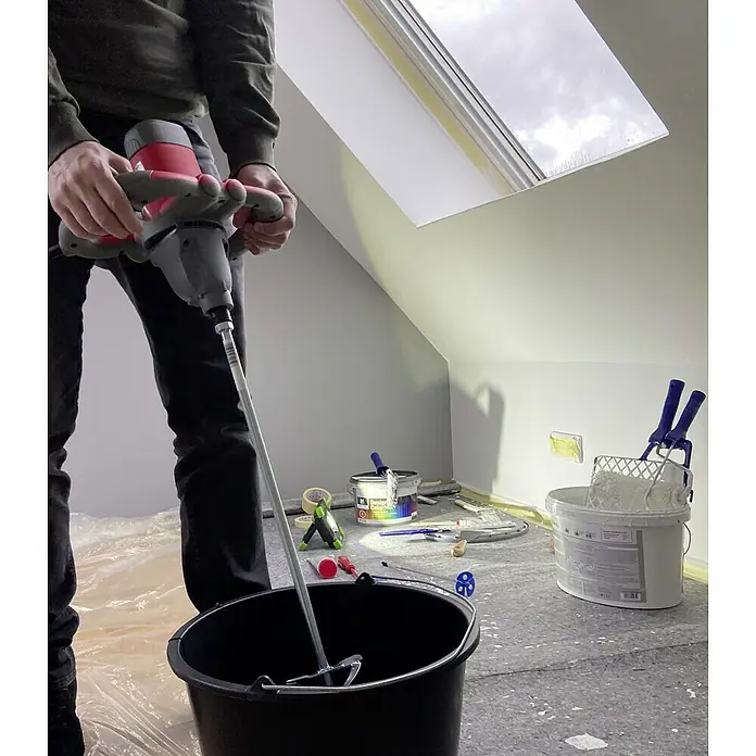 Berg Tecmix Handrührwerk TMX PRO 1250 - Durchmesser Rührer: 120 mm, Leistungsaufnahme: 1.200 W - Ein Mann mischt Farbe mit einem Farbmischer in einem Raum mit Malereibedarf.