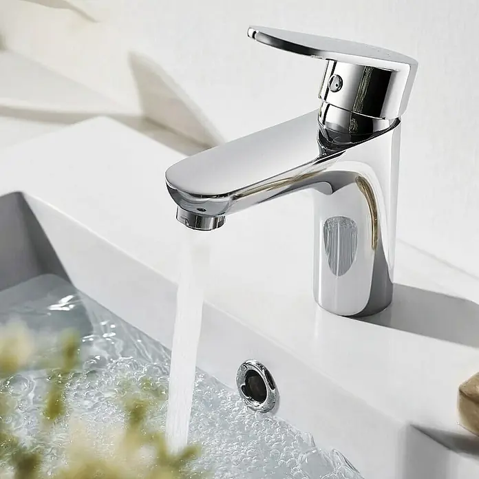 Home Deluxe Waschtischarmatur RADIANT - Chrome - Nahaufnahme einer glänzenden, modernen Armatur auf einem weißen Waschbecken, aus der Wasser fließt. Perfekt für stilvolle Badezimmer.