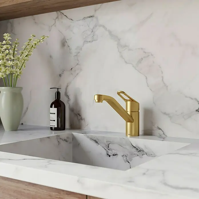 Lenz Spültischarmatur Mila - Gold, Matt - Nahaufnahme einer modernen Küchenarmatur in Goldoptik, eingebettet in eine elegante Marmorarbeitsplatte, neben einer Vase mit Blumen.
