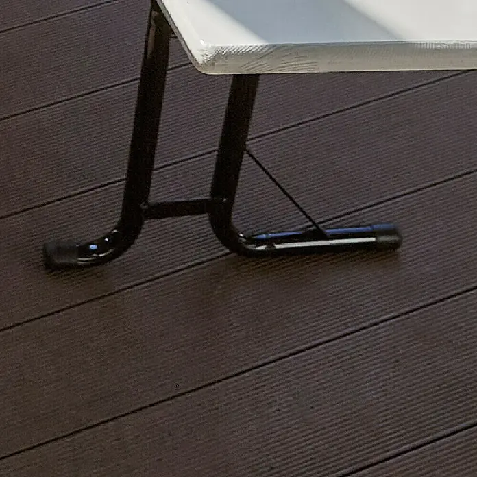 Bierzeltgarnitur - 3 -tlg., Fichte/Stahl, Klappbar, Beige/Grau, Tisch (L x B x H): 220 x 70 x 77 cm, Bank (L x B): 220 x 30 cm - Detailaufnahme eines weißen Klapptisches mit schwarzen Metallbeinen auf einem dunklen Holzboden.
