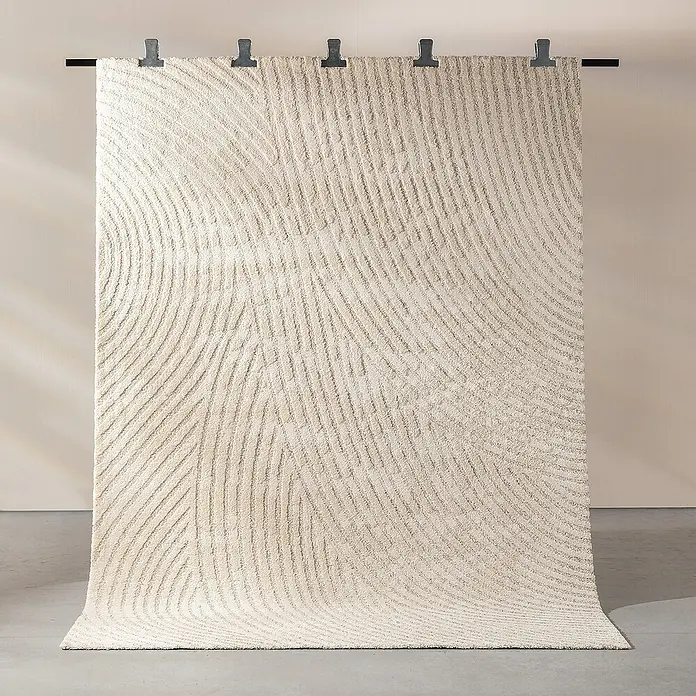 Dekoria Flachgewebeteppich - creme, beige - Nahaufnahme eines elfenbeinfarbenen Teppichs mit gewundenen, strukturierten Linien und Aufhängern an einer Stange.