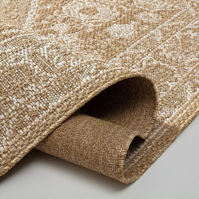 Dekoria Flachgewebeteppich - karamellfarben, 230 x 160 cm - Nahaufnahme eines beigen Teppichs mit gewebtem Muster und gerolltem Rand, der die Textur und Verarbeitung hervorhebt.