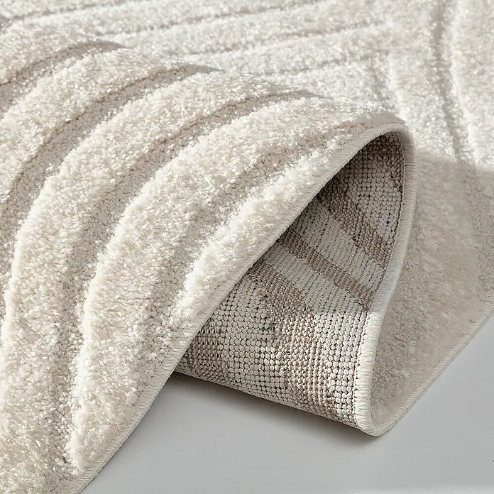 Dekoria Flachgewebeteppich - creme - Nahaufnahme eines elfenbeinfarbenen Teppichs mit erhabenem Streifenmuster, der seine Textur und sein Design hervorhebt.